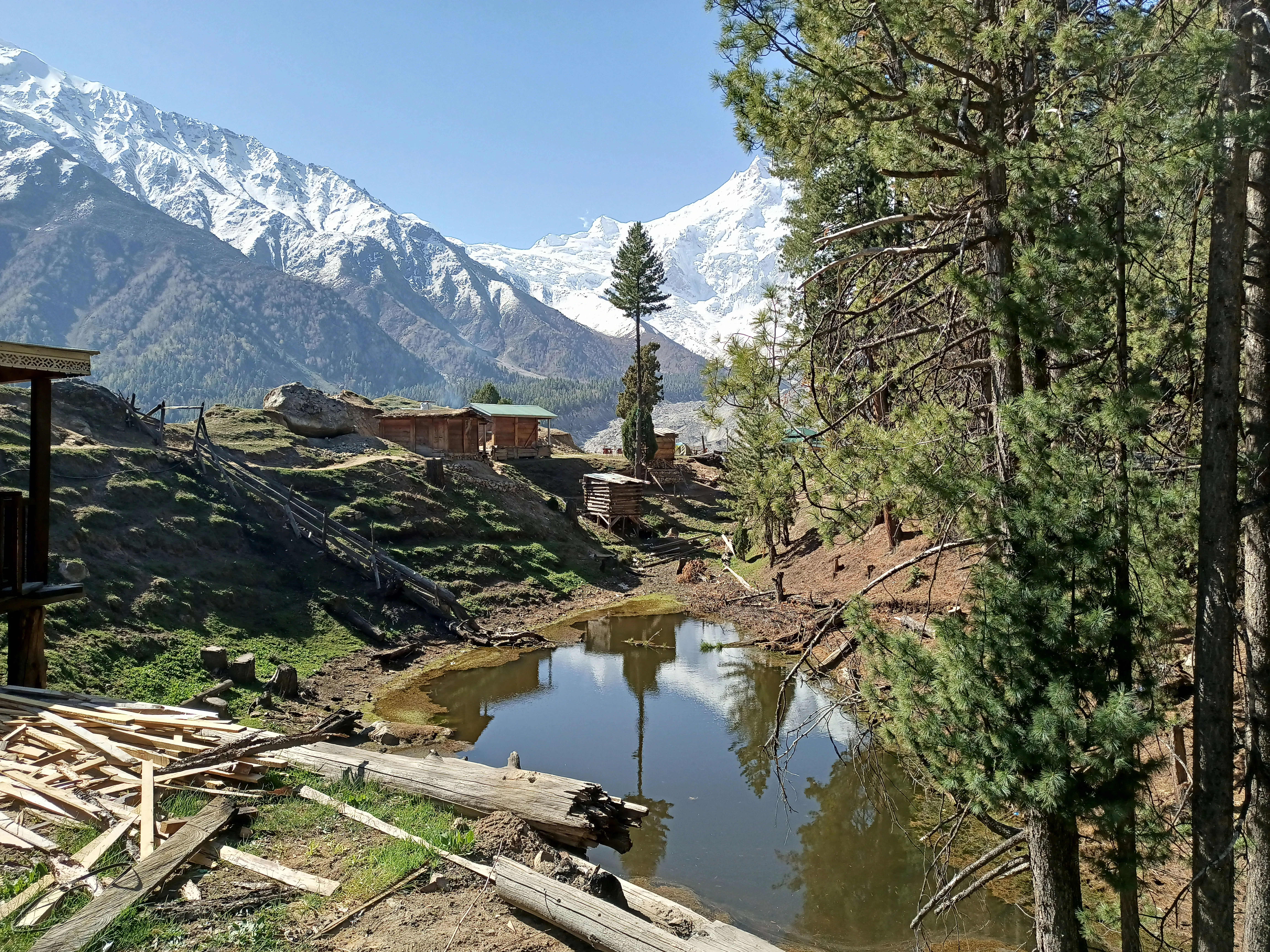 Reflecting pond and cabins below a snow peak near Skardu
