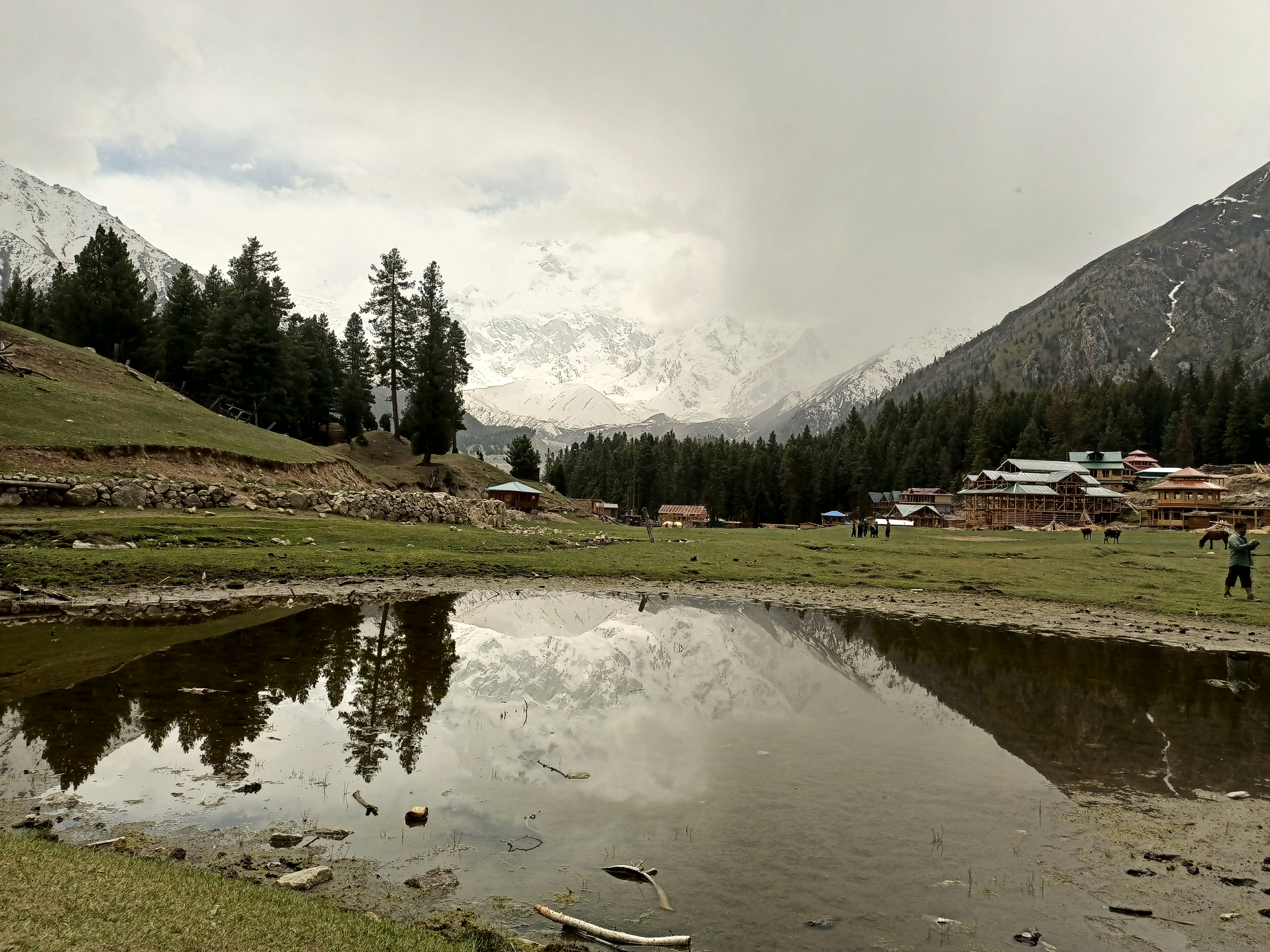 Still water reflecting a northern Pakistani village at dusk