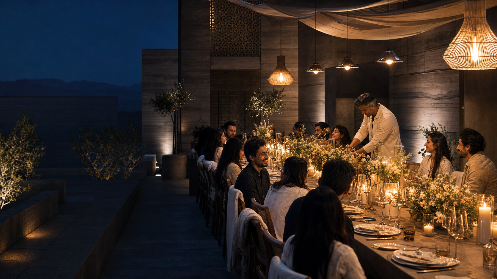Friends sharing a bespoke candlelit dinner in a contemporary courtyard